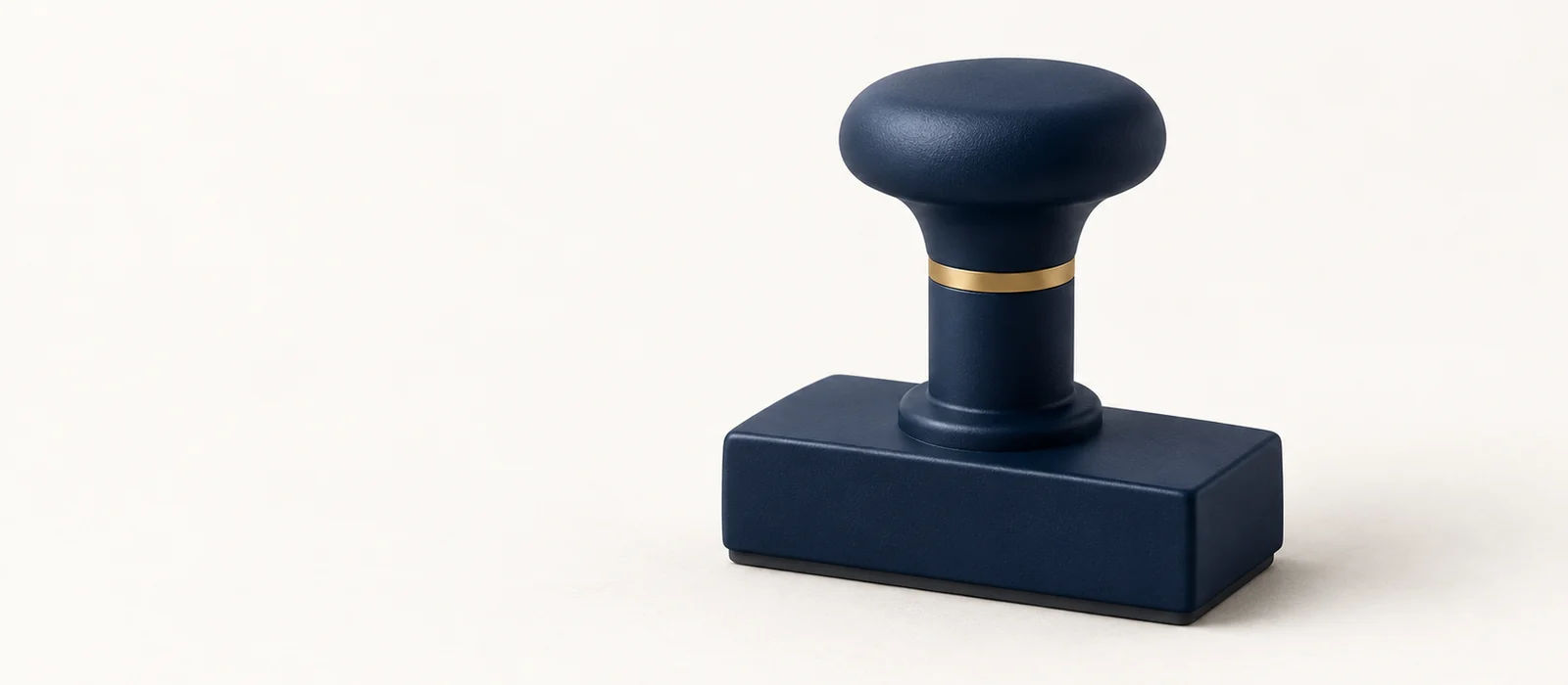 A matte navy rubber stamp with a thin gold band, on warm paper.