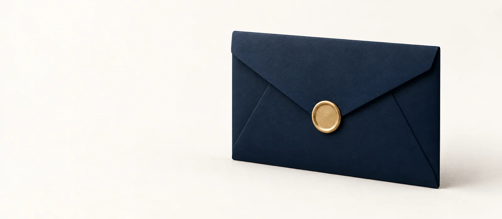 A matte navy envelope with a small gold wax seal, on warm paper.