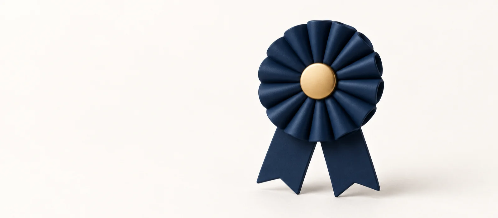 A matte navy rosette ribbon badge with a gold centre, on warm paper.