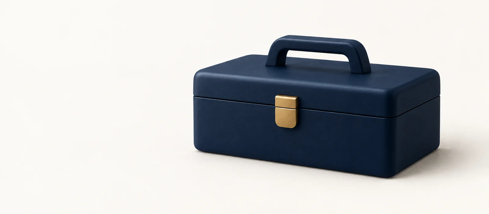 A closed matte navy toolbox with a gold latch, on warm paper.