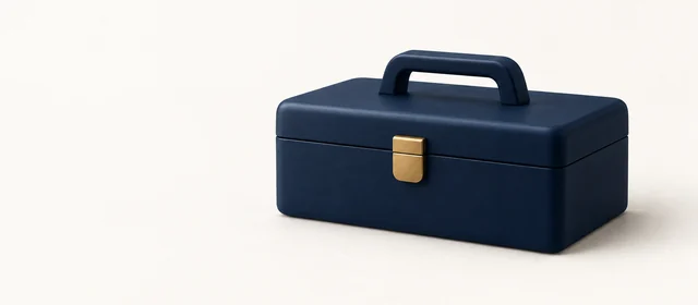 A closed matte navy toolbox with a gold latch, on warm paper.